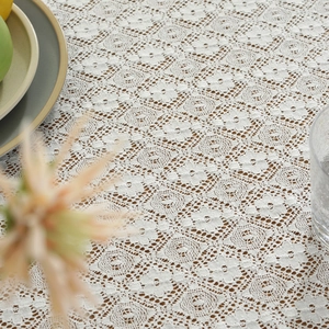 White cotton lace tablecloth with vintage floral embroidery on a rustic wooden table