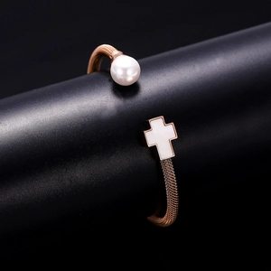 Makro-Detail von Roségold-Kabelarmband mit weißer Perle und Kreuz-Anhängern
