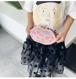 Close-up of pink lip-shaped sequin bag for kids with gold chain and colorful patterns