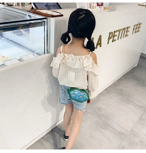 Girl wearing a green cartoon crossbody bag with golden chain strap in a bright shop