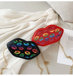 Close-up of red and black glitter lip-shaped crossbody bags with gold metal chains