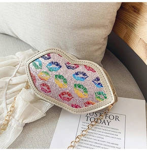 Detail of pink glitter lip-shaped crossbody bag with colorful prints and gold chain strap