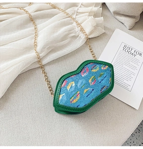 Detail of colorful lip-shaped glitter bag with green edges and a gold chain strap