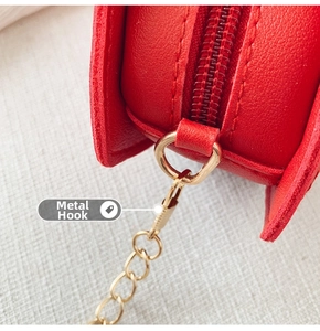 Detail of red leather mini bag with gold chain hardware and secure metal clasp