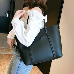 Detail of a large black PU leather bucket tote bag with stylish vertical stitching