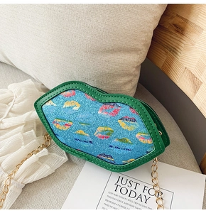 Detailed close-up of a blue glitter lip-shaped crossbody bag with gold chain on a sofa