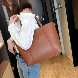 Brown leather tote bag lifestyle shot showing large capacity and minimalist design