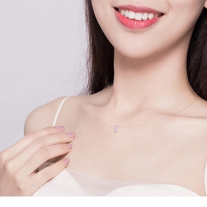Detailed view of invisible fish line necklace with a sparkling teardrop zircon on a model
