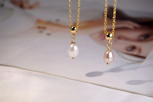 Detailed close-up of golden teardrop freshwater pearl pendants in white and pink hues