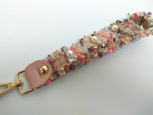 Close-up of woven wrist strap with pearl charms and golden metal lobster clasp
