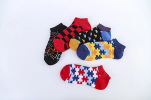 Detailed top view of five pairs of men's colorful geometric pattern ankle socks on white