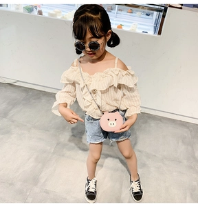 Toddler girl wearing a cute pink pig cartoon crossbody bag in a bright bakery setting
