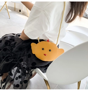 Detail shot of a yellow cartoon chick crossbody bag on a child model with smooth leather texture
