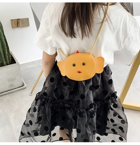 Kid's yellow fish-shaped PU leather crossbody bag worn by a child in a home setting
