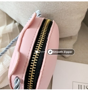 Detail of light pink mini bag showing the smooth metal zipper and woven shoulder strap