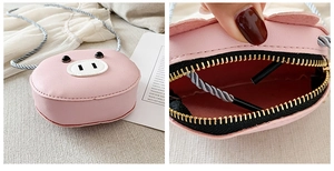 Detail of pink pig-shaped mini kid purse showing gold metal zipper and black lining