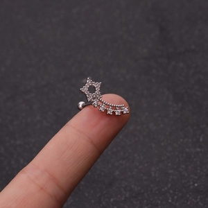 Minimalist silver star cartilage earring with zircons held on a fingertip for scale