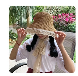 Close-up of a beige straw sun hat featuring delicate lace trim and matching ribbon ties