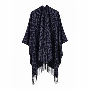 Detailed view of grey and black leopard print knit poncho with decorative long tassels