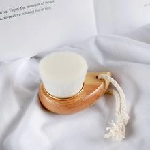 Detail of wooden facial brush with white bristles and cotton rope on soft fabric