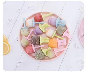 Close-up of DIY fruit popsicles with colorful animal-shaped handles in a pink tray