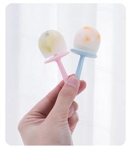 Close-up of two mini DIY popsicles with fresh fruit pieces and colorful handles