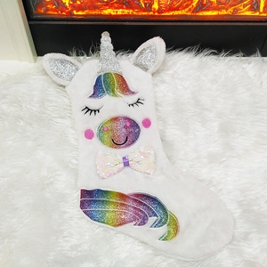 Detail of white plush unicorn Christmas stocking with rainbow sequins on a cozy rug