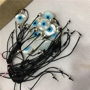 Detailed stack of woven evil eye bracelets with mother of pearl shell charms and beads