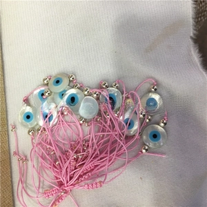 Detail of pink woven evil eye bracelets with white mother of pearl shell charms