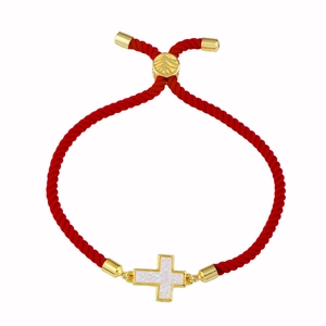 Dettaglio di un bracciale a corda rossa intrecciata con pendente a croce dorata regolabile