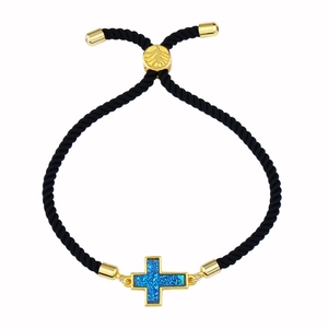 Dettaglio del ciondolo a croce con intarsio blu su bracciale a corda nera regolabile