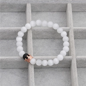 Detail of beaded crown bracelet with black matte beads and rose gold crown on velvet