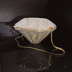 Macro shot of silver diamond-shaped evening clutch with crystal rhinestones on a mirror base