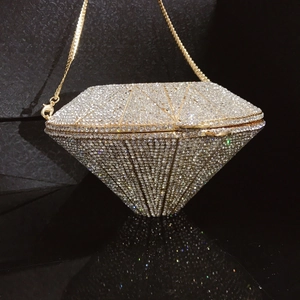 Detailed close-up of diamond-shaped clutch with gold metal frame and sparkling crystals