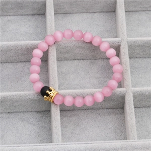 Detail of pink cat-eye stone bead bracelet with a gold CZ crown charm in a jewelry box