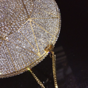 Close-up of geometric diamond-patterned evening clutch with silver crystals and gold chain