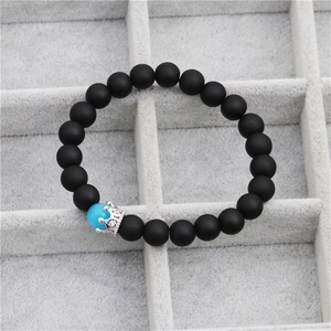 Detailed macro view of black frosted bead bracelet with silver crown charm and blue opal bead