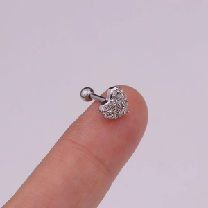 Macro detail of a heart-shaped zircon ear stud with silver screw back on a finger