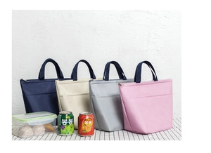 Row of insulated lunch bags in navy, beige, grey, and pink colors on checkered desk