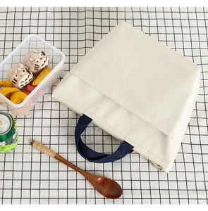 Beige insulated oxford lunch bag with navy handles and zipper shown on checkered mat