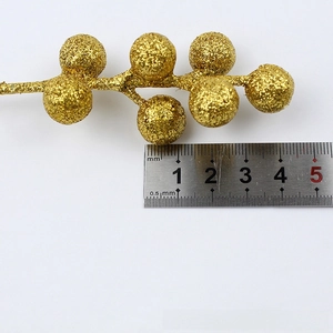 Detail of gold glitter berry stems showing individual berry size with a metal ruler