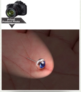 Detail shot of a polished silver stud earring with a dark blue faceted gemstone