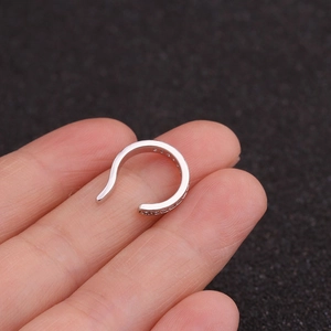 Gros plan sur un ear cuff en U argenté serti de zircons pour oreilles non percées