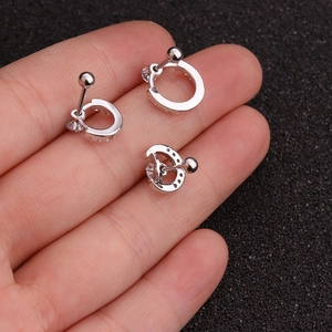 Three silver stainless steel ball end earrings with zircon crystals held on fingertips