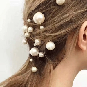 Detailed view of elegant white pearl U-shaped hair pins styled in a bride's long hair