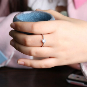 Close-up of a silver classic six-prong solitaire ring with a round zircon on a warm background