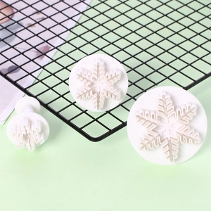 Detailed view of 3-piece white snowflake plunger cutters for baking cookies and fondant