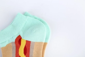 Close-up of cotton blend crew socks in mint green and red with a casual summer pattern