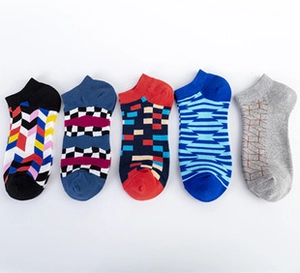 Flat lay of five patterned low cut socks in black, blue, and red with geometric designs