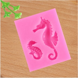 Top view of a pink silicone mold featuring two seahorse shapes on a wood background